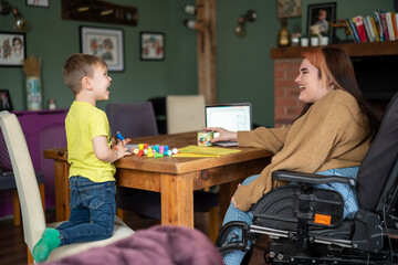 Woman on wheelchair sitting at table with son