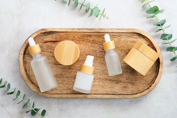Wall Mural - natural cosmetics set on wooden plate with eucalyptus leaves on stone table. top view herbal spa bea