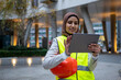 UK, London, Female engineer in hijab and reflective clothing using tablet