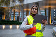 UK, London, Female engineer in hijab and reflective clothing using tablet