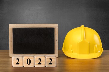 Canvas Print - Happy New Year 2022 Construction and Industry. Helmet and a numbered cube on the desk