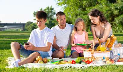 Wall Mural - Happy young parents with two teenagers having a picnic on the countryside. High quality photo