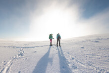Two Women Walk In Snowshoes In The Snow
