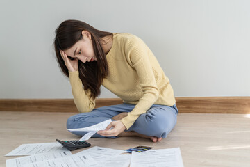 Financial owe asian woman, female sitting on floor home, stressed and confused by calculate expense from invoice or bill, have no money to pay, mortgage or loan. Debt, bankruptcy or bankrupt concept.