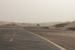 Dusty desert road in sand storm with car