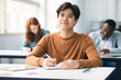 © Prostock-studio - Smiling asian student sitting at desk in classroom