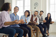 © Studio Romantic - A group of young office colleagues at a seminar, smiling and applauding their male colleague for an emotional story. Happy man tells his colleagues his business path, sitting in a line in the office.