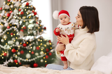 Poster - Happy young mother with her cute baby on bed, space for text. Winter holiday