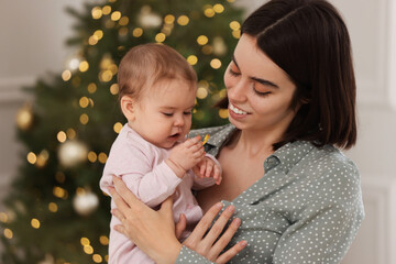 Poster - Happy young mother with her cute baby against blurred festive lights. Winter holiday