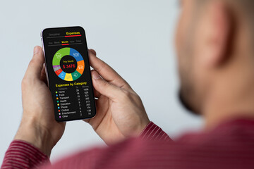 Man with cellphone calculating family monthly spendings