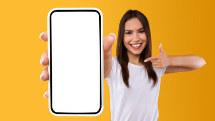 Wall Mural - Woman showing white empty smartphone screen and pointing