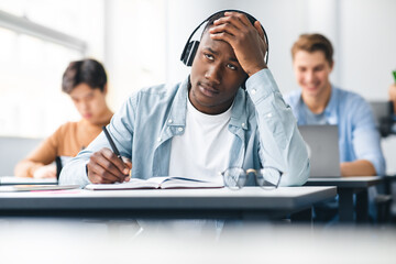 Wall Mural - Black male student writing sitting at desk in class