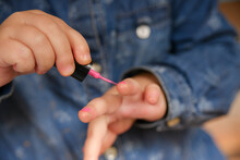 Little Child Paints Nails With Nail Polish. Children Use Parental Cosmetics To Look Like Adults.