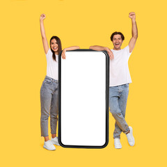 Wall Mural - couple showing white empty smartphone screen and making win gesture