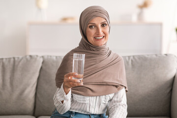 Wall Mural - Muslim Woman Posing Holding Glass Of Water Drinking At Home