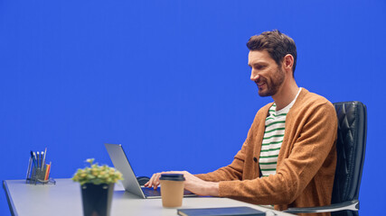 Poster - Green Screen Office Background: Caucasian Businessman Sitting at His Desk Working on a Laptop Computer. White Man working with Big Data e-Commerce Analysis.