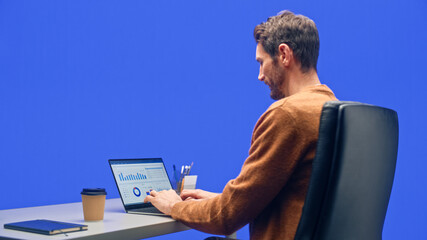 Poster - Green Screen Office Background: Caucasian Businessman Sitting at His Desk Working on a Laptop Computer. White Man working with Big Data e-Commerce Analysis.