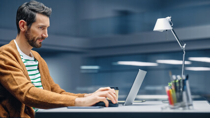Poster - Modern Office: Handsome Businessman Sitting at His Desk Working on a Laptop Computer. Man working with Big Data e-Commerce Analysis. Motion Blur Background Showing Active Work Day.