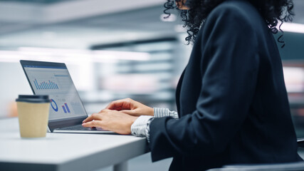 Poster - Modern Office: Black Businesswoman Sitting at Her Desk Working on a Laptop Computer. Successful African American Woman working with Big Data e-Commerce. Motion Blur Background