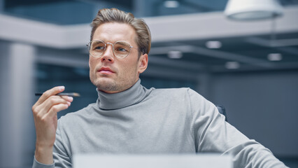 Poster - Modern Office: Thoughtful Businessman Sitting at His Desk Working on a Laptop Computer, Finding Problem Solution. Digital Entrepreneur working on e-commerce Startup. Blurred Background.