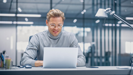 Poster - Modern Modern Office: Businessman Sitting at His Desk Working on a Laptop Computer. Digital Entrepreneur working with Big Data e-Commerce Project, Successful Startup. Blurred Background.