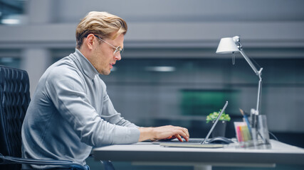 Poster - Modern Office: Portrait Businessman Sitting at His Desk Working on a Laptop Computer. Man working with Big Digital Data e-Commerce. Energetic day with Blurred Motion background