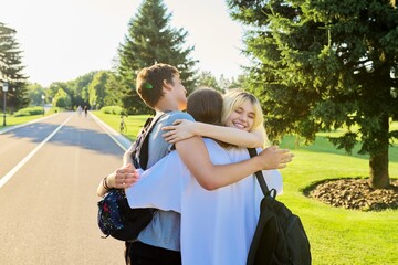 Wall Mural - Happy teenage friends hugging together on a sunny day in the park.