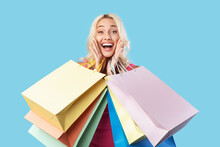 Excited Blonde Woman Holding Shopping Bags At Studio