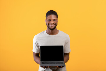 New website. Excited black man holding laptop computer with black screen, showing free copy place for your mockup design