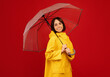 © Prostock-studio - Autumn mood concept. Happy lady standing under transparent umbrella, smiling and looking at camera over red background