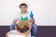 Handsome  Asian male seafood seller wears white hat and green apron, holds fresh crabs in hands. Concept : food sale, local small business in Thailand. Copy space for text.                 