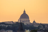 Fototapeta Londyn - Saint Peter's Basilica dome seen from the Orange Trees Garden (Giardino degli Aranci) at sunset with an orange clear sky