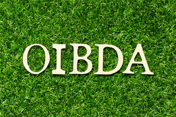 Poster - Wood letter in word OIBDA (Abbreviation of .Operating Income Before Depreciation and Amortization) on green grass background