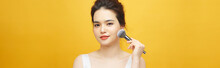 Beautiful Woman Holding Makeup Brush Over Yellow