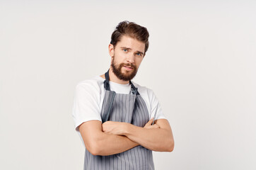 Wall Mural - confident hairdresser in an apron with a comb and scissors in his hands gestures with his hands and styling his hair