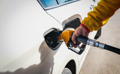 Man pumping gasoline fuel in car at gas station and being fill gas tank of white car in gas station, Concept of Global Fossil Fuel Consumption, Rising gasoline prices, Copy Space.