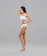 © Acronym - Attractive and slender brunette girl in white underwear posing in studio. Healthy lifestyle, sport and body care concept.