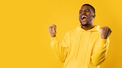 Wall Mural - Emotional Black Man Shouting Shaking Fists Celebrating Success, Yellow Background