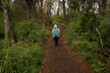 © Gonzalo - Taking a walk in the forest. View of a young woman hiking along the path in the woods.