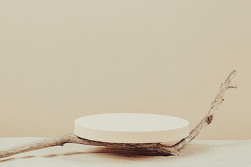 Empty round beige platform podium and dry tree twigs on white beach sand background. Minimal creative composition background for cosmetics or products presentation. Front view