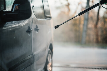 Wall Mural - Manual car wash with white soap, foam on the body. Washing Car Using High Pressure Water.