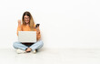 © luismolinero - Young woman with a laptop sitting on the floor with phone in victory position