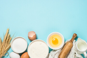 Wall Mural - Ingredients for cooking baking at blue table. Flour, sugar, eggs and utensils. Top view with copy space.