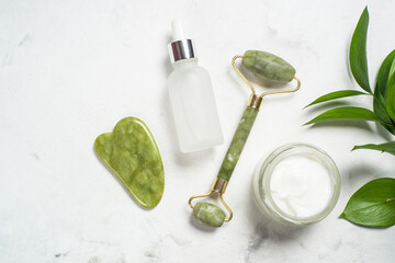 Fototapete - Scincare product. Jade roller and gua sha stone massager with face cream and serum bottle. Anti aging therapy. Top view.