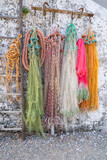 Fototapeta  - Close up of old fishing nets in orange green purple  pink orange and white hanging on a wall