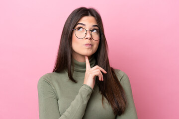 Young Brazilian woman isolated on pink background With glasses and looking up