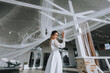© shchus - Wedding photography, portrait of a beautiful brunette bride in a white dress with a long veil in her hands in sunny weather against the backdrop of a wooden house in a park in nature.