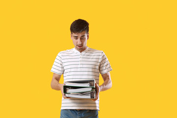 Poster - Shocked young man with folders on yellow background