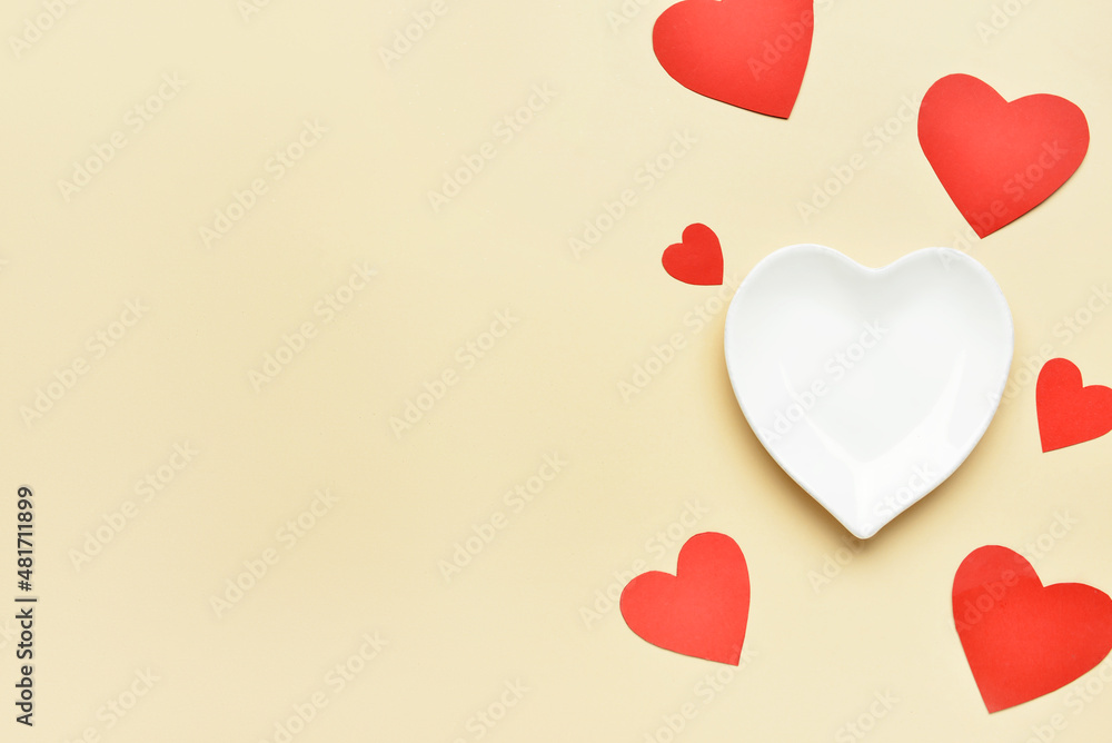 Beautiful heart-shaped plate on beige background
