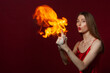 © Roman Kornev - A young woman with long brown hair, in a red dress on a red background with fire